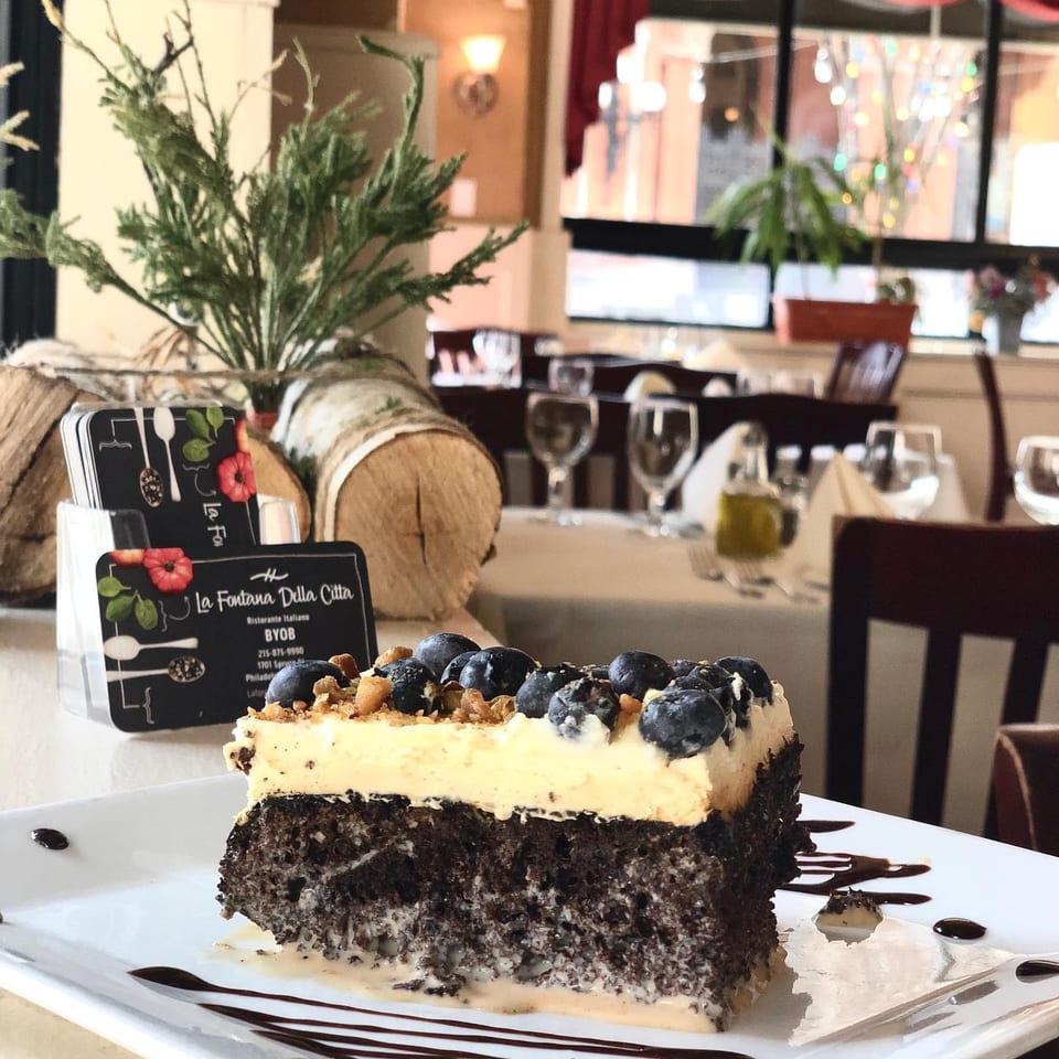 Blueberry-topped chocolate dessert with creamy filling and chocolate drizzle served in an elegant Italian restaurant.